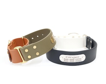 May include: Three dog collars in different colors: olive green, white, and navy blue. The olive green collar has a brown leather accent and gold-colored hardware. The navy blue collar has a silver nameplate with the name "Ginger" and a phone number.
