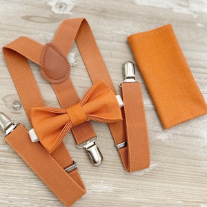 May include: A set of orange suspenders with a matching bow tie and pocket square. The suspenders have adjustable clips and a leather strap.