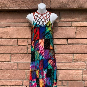 May include: A colorful patchwork maxi dress with a tie-dye pattern. The dress has a halter neckline with a criss-cross strap detail.