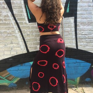 May include: A black skirt with a red tie-dye pattern and a side slit. The skirt is long and flowy, and it has a high waist.