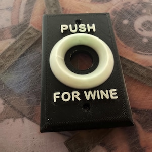 May include: Black plastic wall plate with a white push button and the text "PUSH FOR WINE".