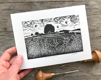 May include: Black and white linocut print of a field with a tree in the distance and birds flying overhead. The print is titled "Harvest Shadows".