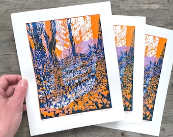May include: Three prints of a woodland scene in orange, blue and white colours. The prints are on white paper and have a white border. The text "Woodland Blue" is printed at the bottom of the prints.