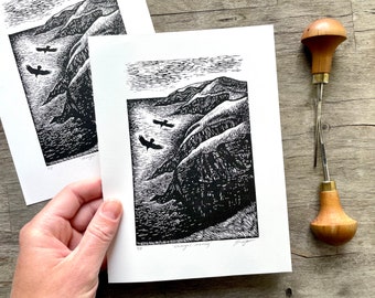 May include: Black and white woodcut print of a coastal scene with three birds flying over a rocky cliff. The print is titled "Choughs Soaring" and is signed by the artist.