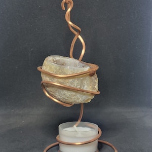 May include: A copper wire candle holder with a natural agate stone. The holder has a swirling design and a small tea light candle sits on the base.