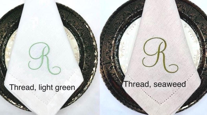 May include: Two cloth napkins, one white and one beige, each folded and placed on decorative plates. The white napkin has a light green embroidered "R", and the beige napkin has a seaweed green "R". The text "Thread, light green" and "Thread, seaweed" are below the napkins.