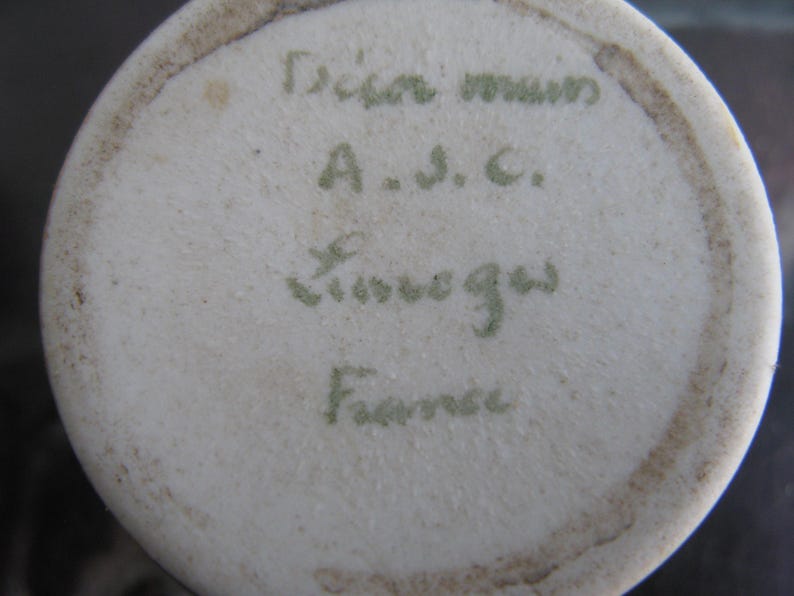 Puede incluir: Primer plano de la base de un jarr&oacute;n de cer&aacute;mica blanca. La base presenta texto manuscrito verde descolorido: "Dian mum, A.S.C., Limoges, France."