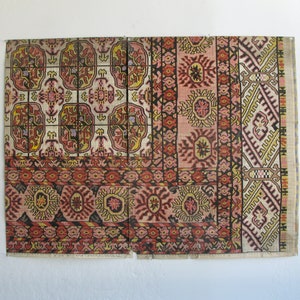 K&ouml;nnte beinhalten: Ein Vintage-Teppich mit einem farbenfrohen geometrischen Muster in Rot-, Rosa-, Gelb- und Blaut&ouml;nen. Der Teppich ist aus gewebtem Stoff gefertigt und hat einen Fransenrand.