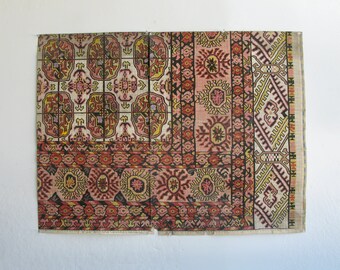 Puede incluir: Una alfombra vintage con un patrón geométrico colorido en tonos rojos, rosas, amarillos y azules. La alfombra está hecha de tejido tejido y tiene un borde con flecos.