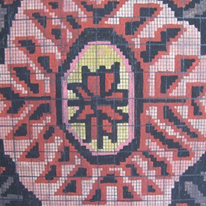 K&ouml;nnte beinhalten: Nahaufnahme eines schwarzen und roten gemusterten Teppichs mit einem Gitternetz dar&uuml;ber. Der Teppich hat ein zentrales Design mit einer gelben und rosa ovalen Form.