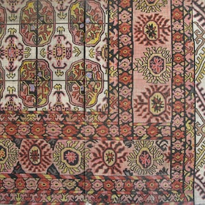 K&ouml;nnte beinhalten: Eine Nahaufnahme eines traditionellen Teppichs mit komplizierten Mustern in Rot-, Rosa-, Gelb- und Schwarzt&ouml;nen. Der Teppich hat ein geometrisches Design mit floralen Motiven.