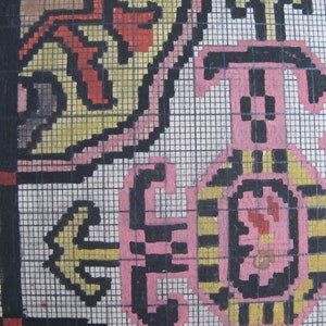 K&ouml;nnte beinhalten: Nahaufnahme einer handgestickten Stickerei mit einem Rastermuster. Das Design zeigt eine Mischung aus schwarzen, wei&szlig;en, rosa, gelben und roten F&auml;den. Das Design ist kompliziert und detailliert, mit einer Vielzahl von Formen und Mustern.