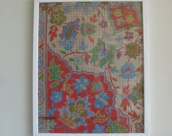 Puede incluir: Obra de arte enmarcada con un detallado patrón floral en tonos rojos, azules, verdes y dorados. El diseño se encuentra sobre un fondo beige con una superposición de cuadrícula, encerrado en un marco blanco. La obra evoca una estética vintage.