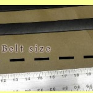 May include: A black leather belt with a metal buckle, measured on a ruler to be 25 inches long. The text "Belt size" is written on the surface below the belt.