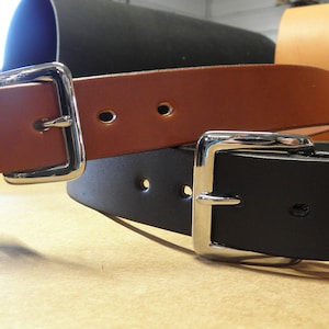 May include: Two leather belts with silver buckles. One belt is brown and the other is black.