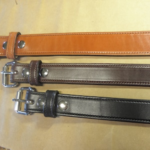 May include: Three leather belts with silver buckles. The belts are brown, dark brown, and black.