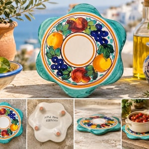 May include: A flower-shaped ceramic trivet featuring a hand-painted border of oranges, peaches, and grapes on a white background with a teal scalloped edge. The underside is white with four small feet and the text DIPA MANO SORRENTO.