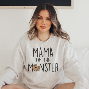 May include: A gray sweatshirt with the text "Mama of the Monster" and a cookie graphic.