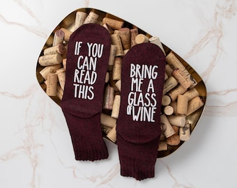Peut inclure: Une paire de chaussettes bordeaux avec du texte blanc. Une chaussette dit "Si vous pouvez lire ceci" et l'autre chaussette dit "Apportez-moi un verre de vin".