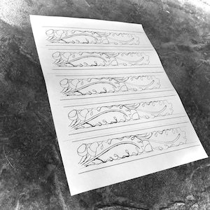 May include: Five black and white line drawings of a stylised leaf design on a white sheet of paper.