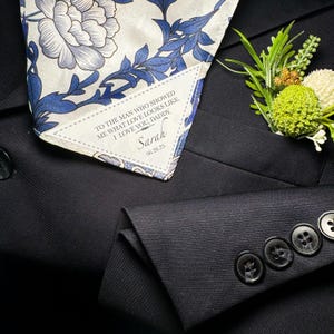 May include: A white pocket square with a blue floral pattern and a personalized message that reads "To the man who showed me what love looks like. I love you, Daddy. Sarah 06.26.25".