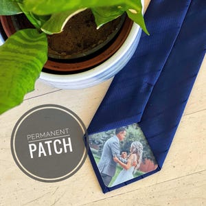 May include: A navy blue tie with a square photo patch of a couple in a field. The text "PERMANENT PATCH" is printed on a gray circle.