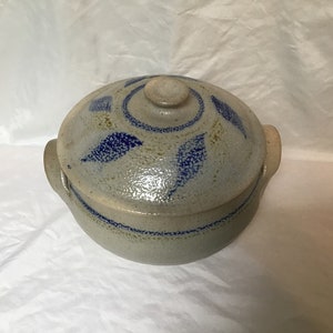 May include: A blue and white ceramic casserole dish with a lid. The dish has a blue and white leaf design and a knob on the lid.