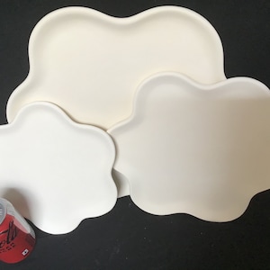Puede incluir: Tres platos de cerámica blanca con forma de flor. Los platos están anidados uno dentro del otro, con el plato más grande en la parte inferior y el más pequeño en la parte superior. Los platos son todos blancos y tienen un acabado liso y brillante.