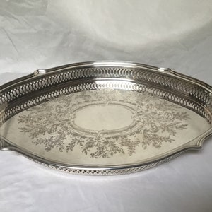 Peut inclure: Un plateau de service ovale en argent avec un motif floral gravé décoratif et une bordure ajourée.