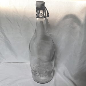 May include: Clear glass bottle with a swing top closure. The bottle has a long neck and a rounded body. Embossed text on the bottle reads "Sparkling Mineral Water Buffalo NY". The bottle is empty and appears to be vintage.