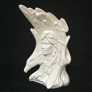 Peut inclure: Sculpture en céramique blanche d'une femme amérindienne avec une coiffe de plumes et deux aigles de chaque côté de sa tête.