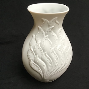 Może przedstawiać: Biały wazon z porcelany z wytłoczonym wzorem stylizowanych liści i kropek.