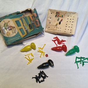 May include: A vintage board game called "Bug" with a partially torn box, game board, and plastic bug pieces in yellow, red, green, and black.