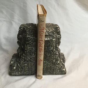 Puede incluir: Un par de sujetalibros de piedra gris con tallas intrincadas, sosteniendo un libro titulado "Mister God, This is Anna".