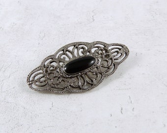 A classic vintage oval brooch with a black centre on a decorative silver tone base, retro brooch, mid century style brooch, old brooch.