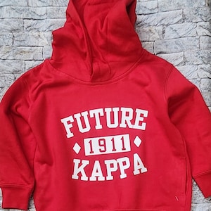 May include: Red hooded sweatshirt with white text that reads "FUTURE 1911 KAPPA".