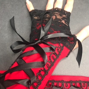May include: Red and black lace fingerless gloves with black ribbon ties. The gloves have a black lace trim and a red fabric base.