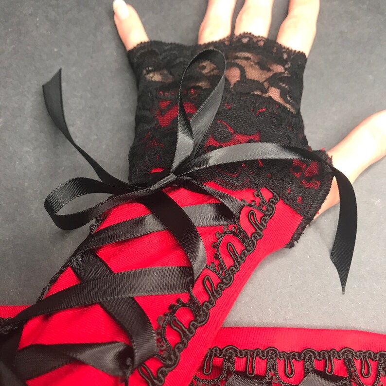 May include: Red and black lace fingerless gloves with black ribbon ties. The gloves have a black lace trim and a red fabric base.