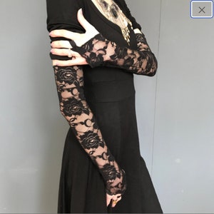 May include: Black lace gloves with floral patterns. The gloves are fingerless and extend to the elbow.