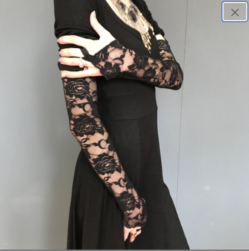 May include: Black lace gloves with floral patterns. The gloves are fingerless and extend to the elbow.