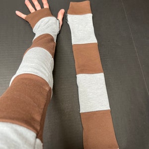May include: A pair of brown and gray striped arm warmers. The arm warmers are made of a soft, stretchy fabric and are perfect for keeping your arms warm in the cooler months.