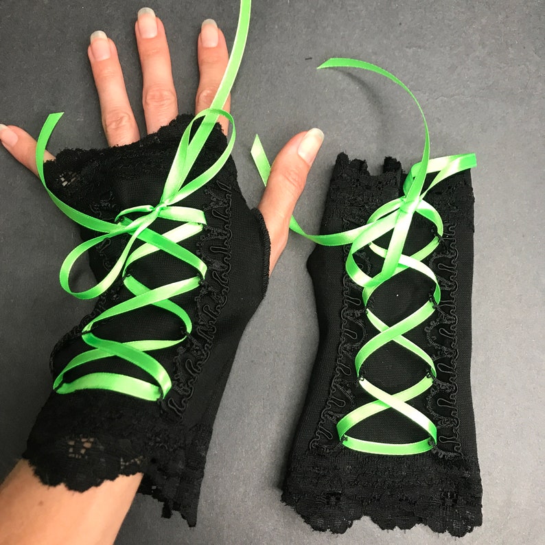May include: A pair of black lace fingerless gloves with green satin ribbon lacing. The ribbon is tied in a bow at the wrist.