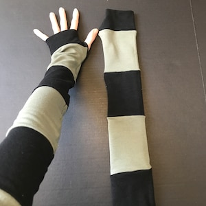 May include: A pair of striped arm warmers in black and olive green. The arm warmers are made of a soft, stretchy fabric and are perfect for keeping your arms warm in the cooler months.