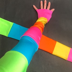 May include: A pair of colorful arm warmers with stripes of green, blue, pink, yellow, and orange. The arm warmers are made of a stretchy fabric and are perfect for adding a pop of color to any outfit.