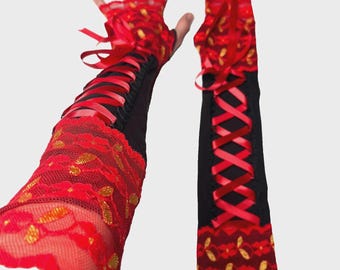 May include: A pair of black fingerless gloves featuring red lace overlays with gold accents. The gloves are designed with a corset-style red ribbon lacing detail running down the center, extending from the wrist to the forearm area.