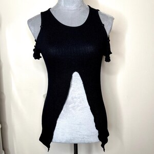 May include: Black ribbed knit top with a unique split front design. The sleeveless top features a round neckline and small shoulder cutouts. The top is displayed on a mannequin.
