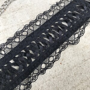 May include: Black lace trim with a woven design. The lace has a scalloped edge.