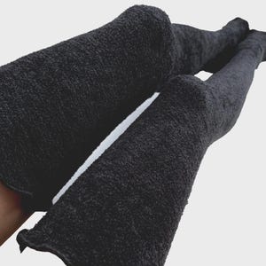 Peut inclure: Une paire de chaussettes noires montant au-dessus du genou, dotées d'une maille épaisse, texturée et duveteuse. Ces longues chaussettes dépassent largement le genou et présentent un aspect doux et pelucheux d'une couleur noire uniforme.