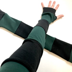 May include: A pair of black and green arm warmers with a striped pattern. The arm warmers are made of a soft, stretchy fabric and are perfect for keeping your arms warm in the cooler months.