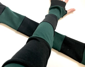 May include: A pair of fingerless arm warmers featuring a color-blocked design with alternating horizontal stripes of solid black and dark forest green fabric. The sleeves extend from the upper arm down to the knuckles, leaving the fingers exposed.